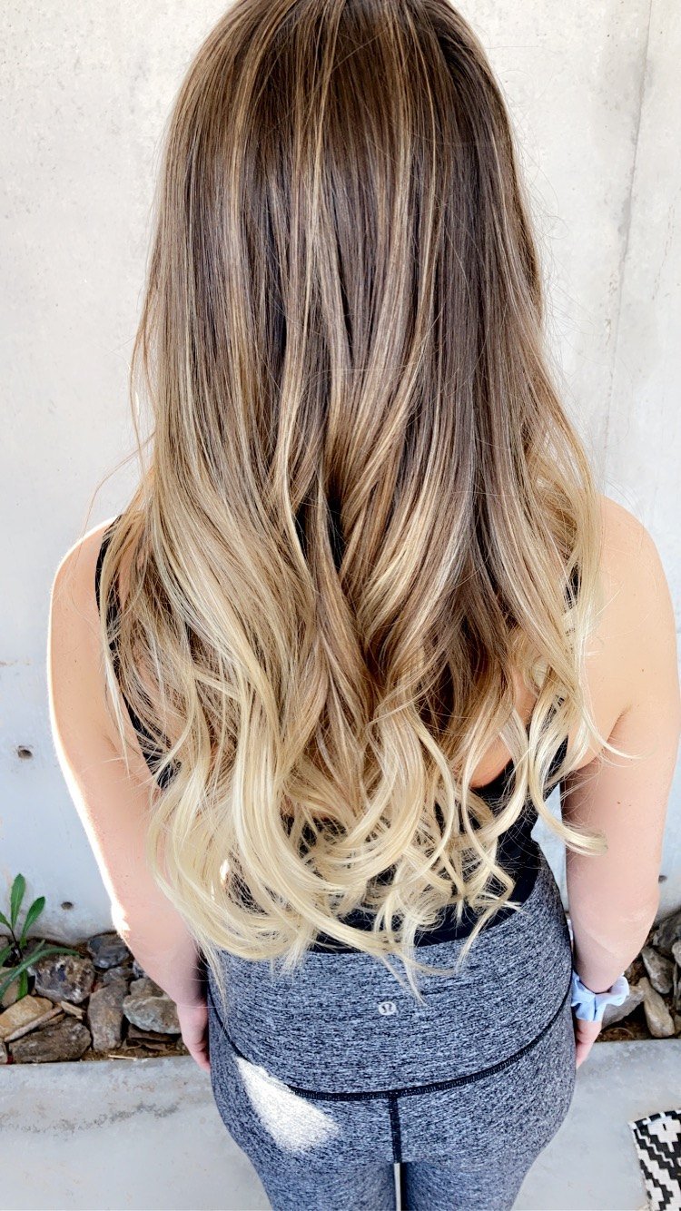 Long blonde balayage with a soft rooted melt and beachy waves