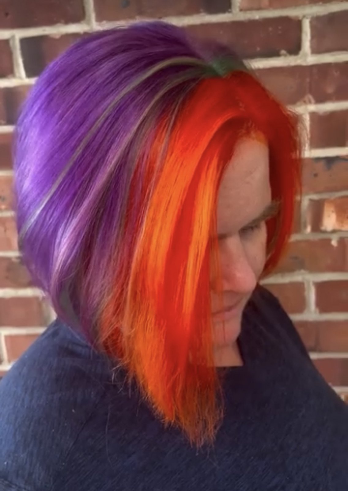 Split vivid hair color in violet and bright orange on a shoulder-length cut